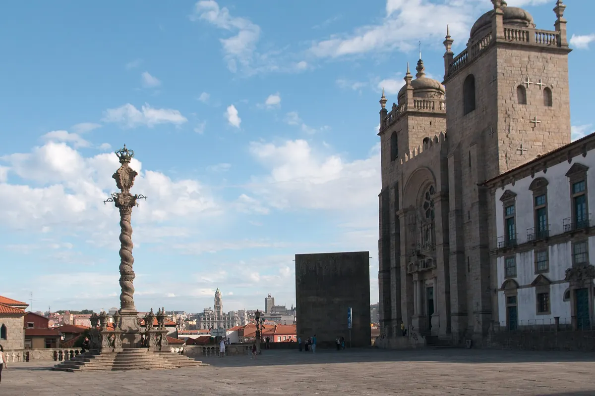 La Cattedrale di Porto e la sua piazza sotto un cielo azzurro, con la colonna della berlina in pietra e le due torri della cattedrale.