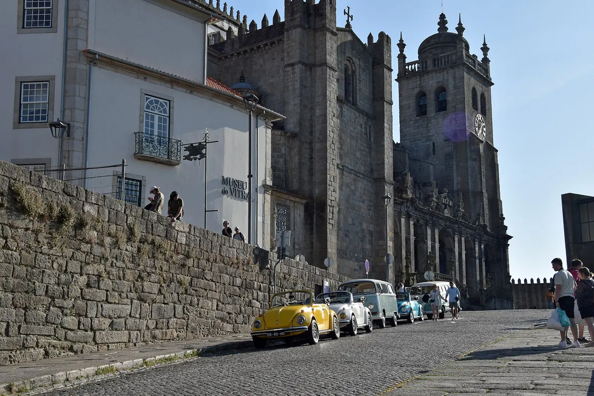 Le torri in granito della Cattedrale di Porto sopra una muraglia e una strada acciottolata.